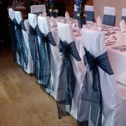 Square-topped chairs with white covers and navy blue sashes